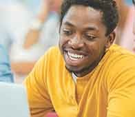 Young man smiling while working on a laptop during study session