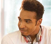 Young man smiling and looking sideways, wearing headphones and white coat