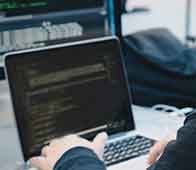Developer typing code on laptop at cluttered desk workspace during a development session