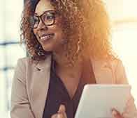 Professional woman holding tablet and smiling in bright office, engaging with a colleague