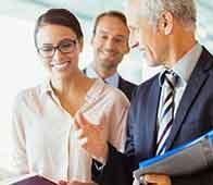 Business colleagues smiling and discussing documents in office corridor