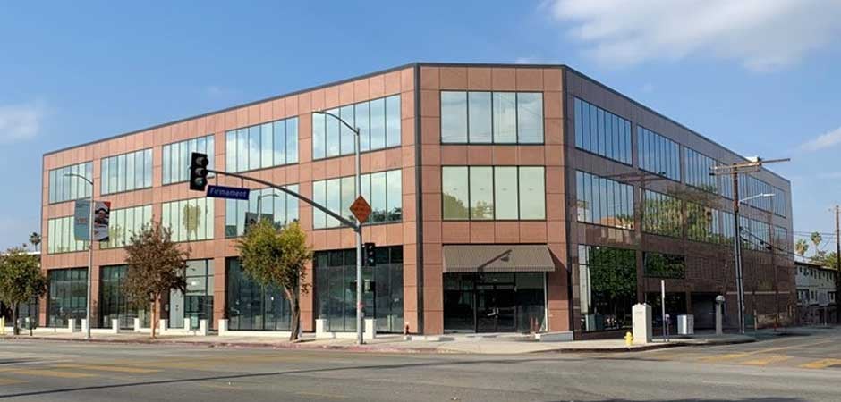 Modern three-story glass-and-brick office building at intersection with traffic light and street sign "Fremont"