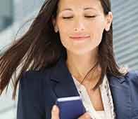 Professional woman checking smartphone with slight smile near modern building facade