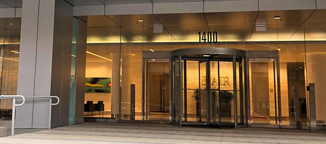 Glass revolving entrance doors beneath "1400" at office building lobby