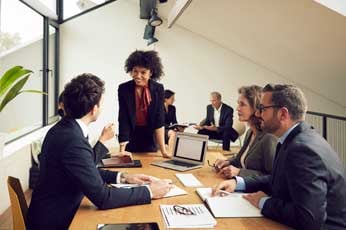 Team meeting with woman leading discussion around table in modern office