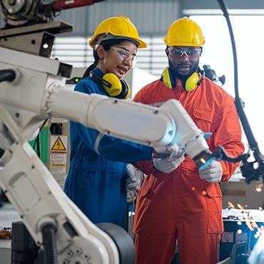 two technicians in an industrial warehouse working with a robotic tool