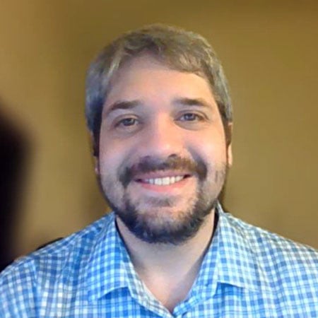 DeVry student Matthew McCloskey, with a beard and mustache, wearing a blue plaid shirt. 