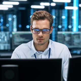 Man with glasses working at a computer.
