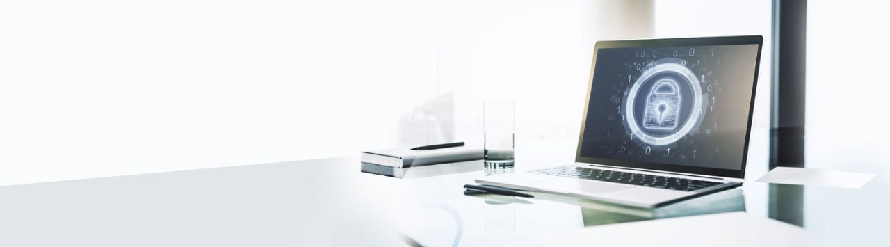 Laptop displaying digital lock icon on glass desk with notebook