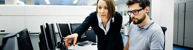 photo of man and woman in office looking at a computer