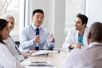 Medical team discussing patient care around a conference table during meeting