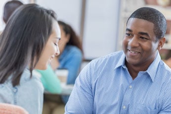 Man smiling and listening to woman during friendly office conversation