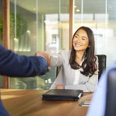 Smiling woman shaking hands with interviewer across conference table