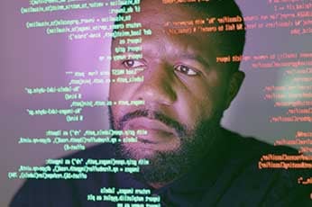 Developer studying floating code projections reflected across his face