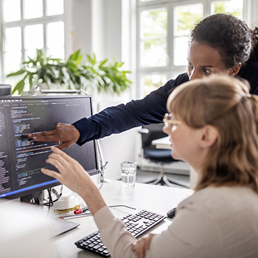 Businesswomen discussing coding on computer