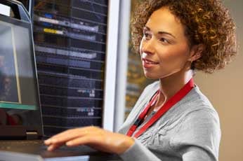 IT technician interacting with laptop beside server racks in a data center