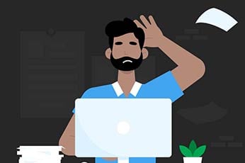 Frustrated man scratching his head at laptop with scattered papers