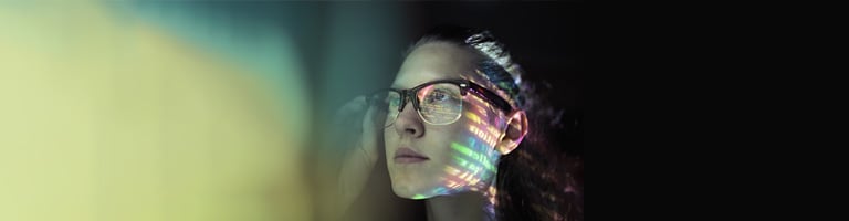 Young woman adjusting glasses with colorful light projections across face