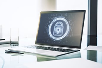 Laptop displaying glowing padlock icon on screen representing data security on glass desk
