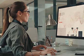 Woman typing at desktop computer in a modern office workspace