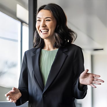 Smiling professional woman gesturing while speaking in a bright modern office by window