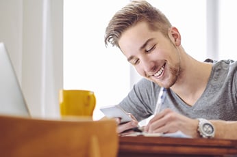 Man looking at phone taking notes