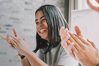 Smiling person clapping enthusiastically at a collaborative team meeting