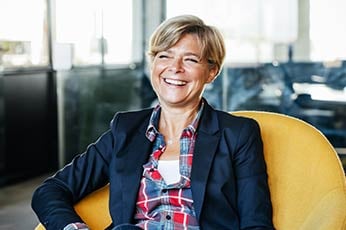 Smiling professional woman seated in yellow chair in modern office