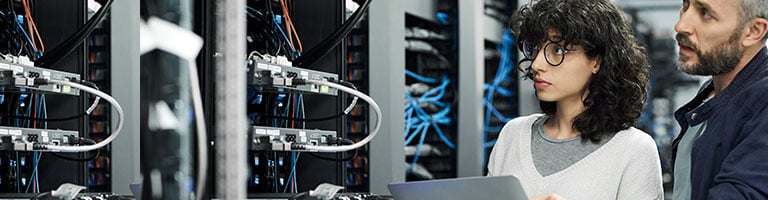 Technicians inspecting server racks with laptop in data center