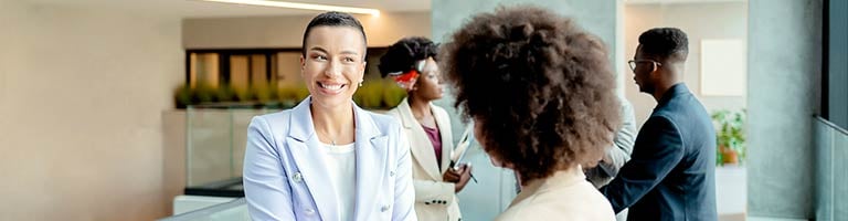 Smiling healthcare professional speaking with colleagues in a modern office lobby