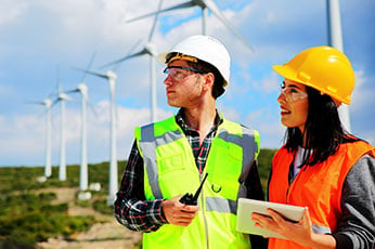 Two renewable energy and sustainable power professionals survey a field of electric windmills