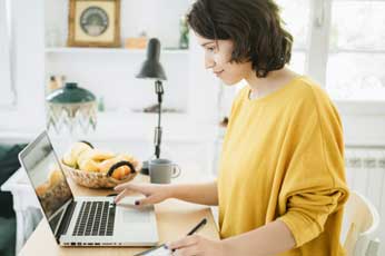 photo of woman in yellow blouse at laptop