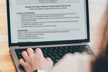 Woman exploring good skills to put on a resume while working on her laptop at a desk.