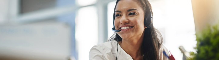 Young woman wearing a headset works on medical billing and coding on her computer.